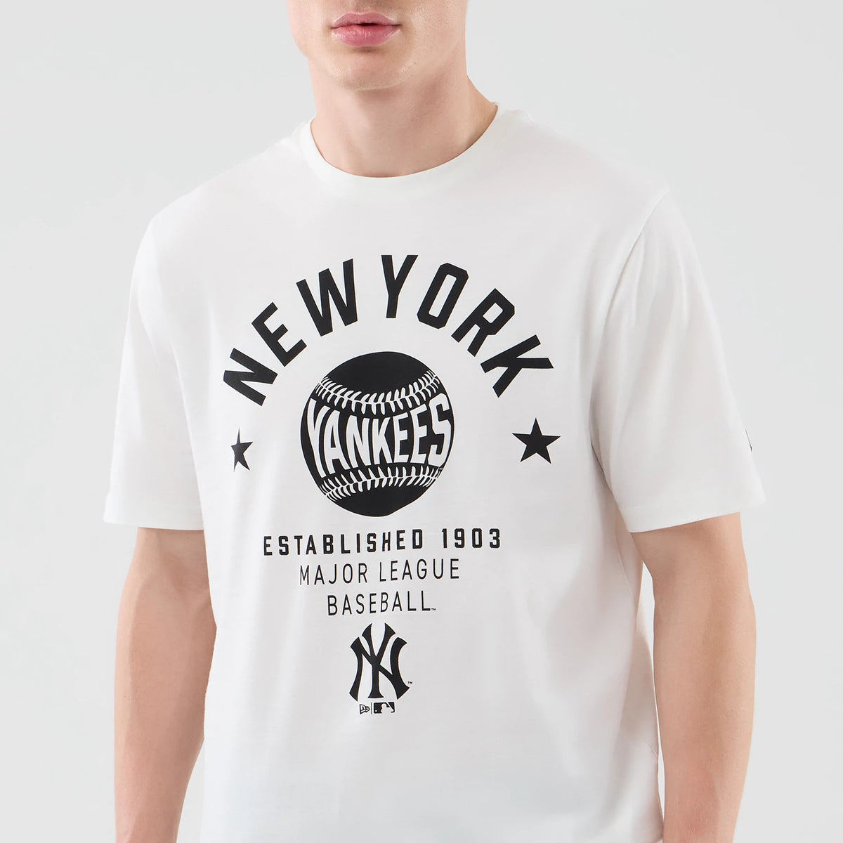 New Era New York Yankees MLB Graphic White T-Shirt, front view on-model featuring a black printed graphic with New York Yankees text above a baseball design, star details, established year and Major League Baseball wording.