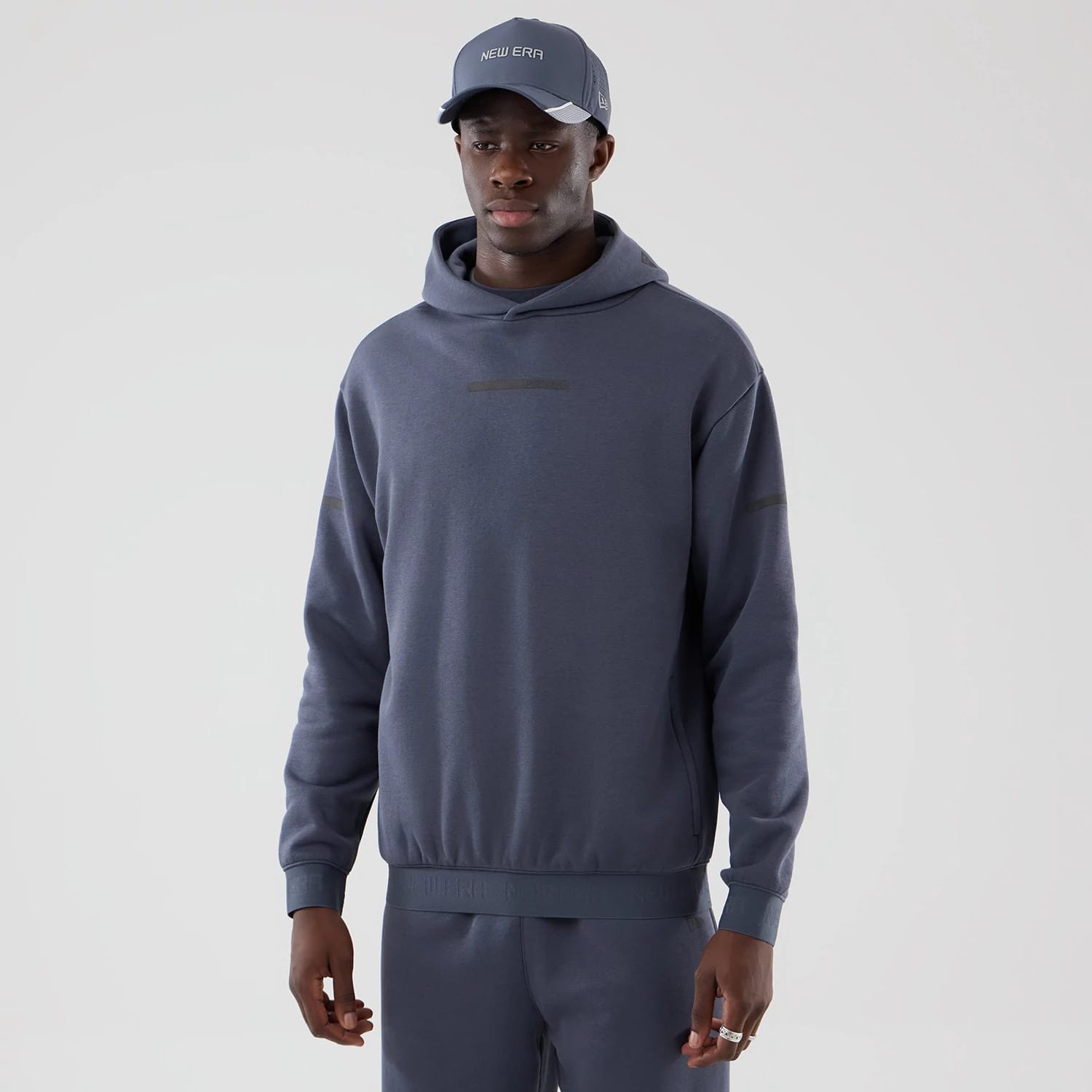 The model is wearing this New Era Tech Oversized Pullover Hoodie in grey. 1