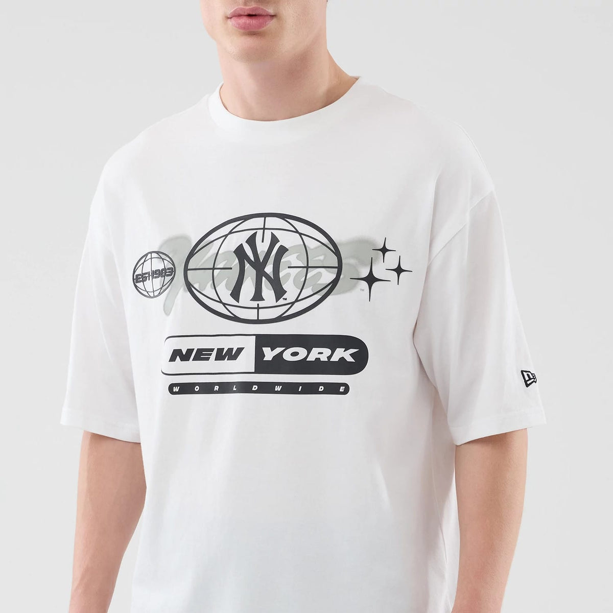 New Era New York Yankees MLB Logo Graphic White Oversized T-Shirt, front view showing large black printed graphics including the Yankees' emblem inside a globe, New York text below, star designs on the right.