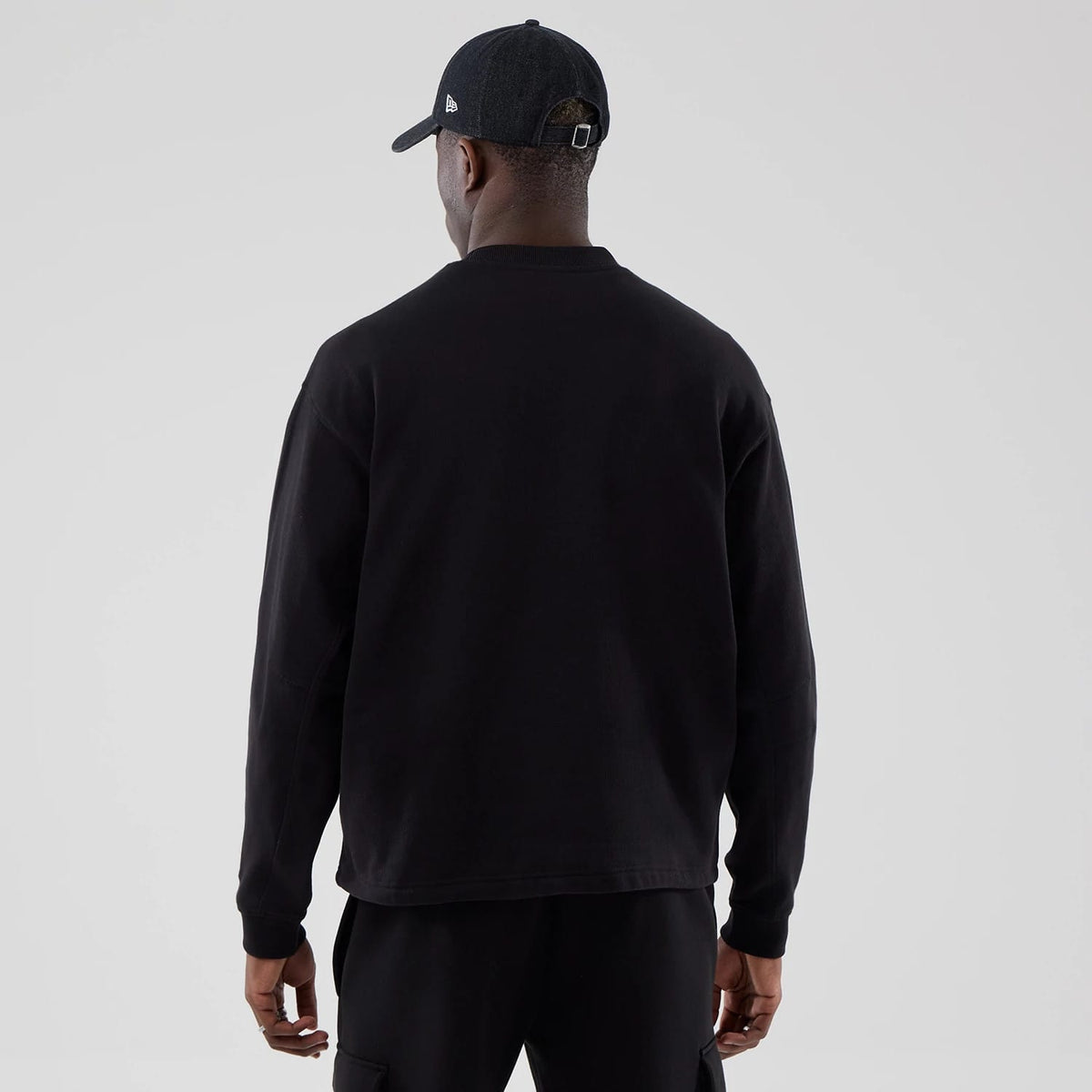 The model is wearing this New Era Oversized Crew Neck Sweater in black. 2