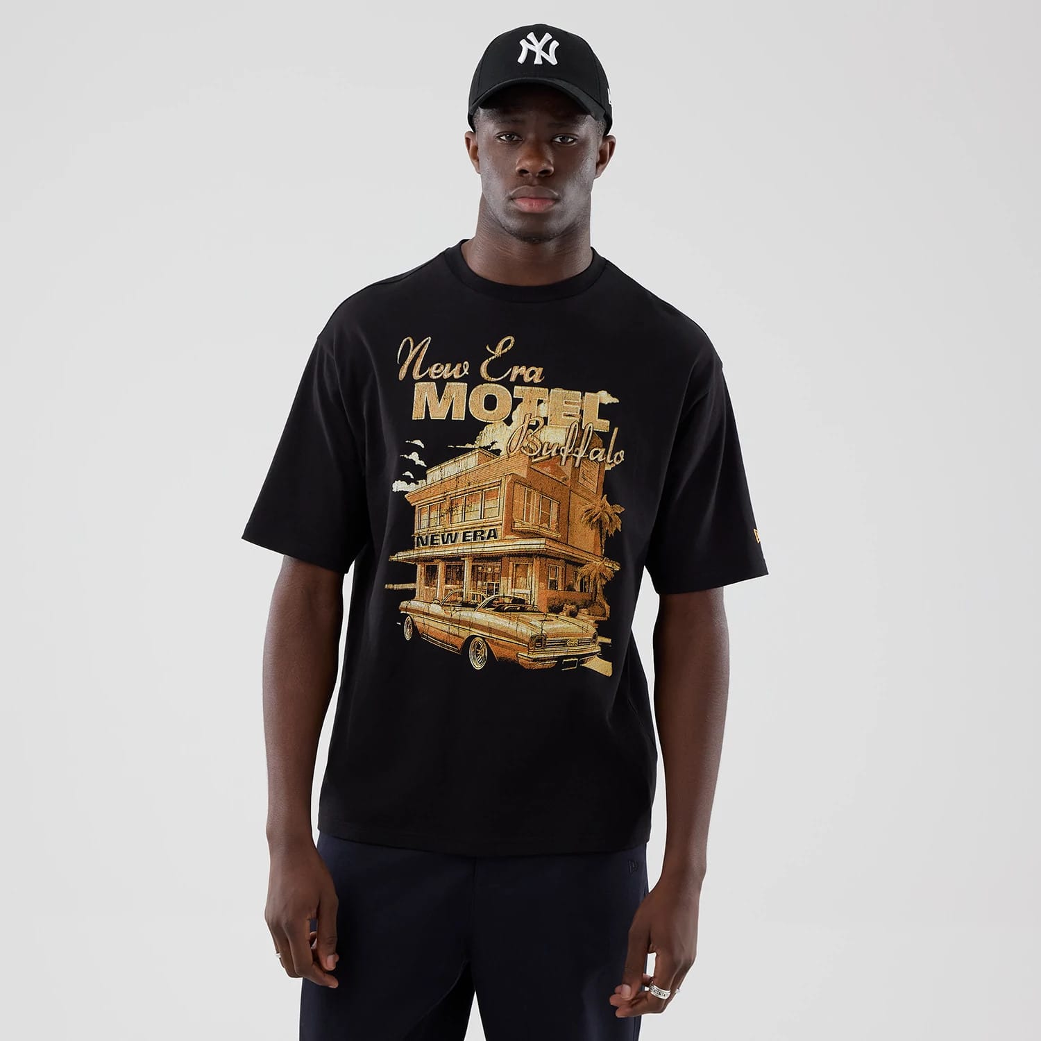 The model is wearing this New Era Motor Graphic Oversized T-Shirt in black. 1