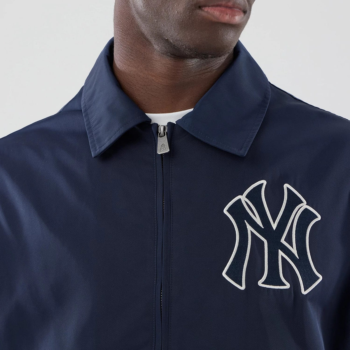 New Era New York Yankees MLB Collared Navy Jacket, front view showing a large white embroidered Yankees logo on the left chest, a pointed collar, and a central zip closure partially under the collar with a small branded pull tab.