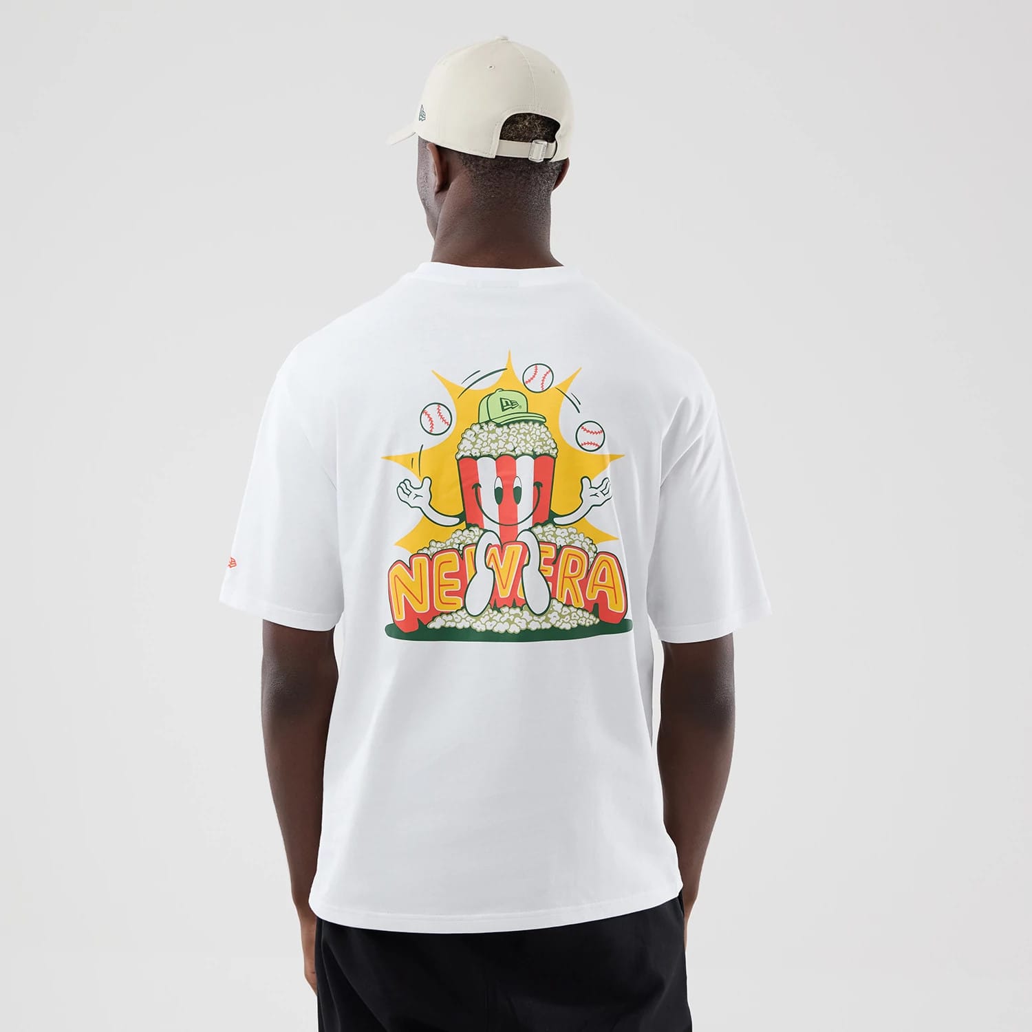 The model is wearing this New Era Baseball Popcorn Graphic Oversized T-Shirt in white. 2