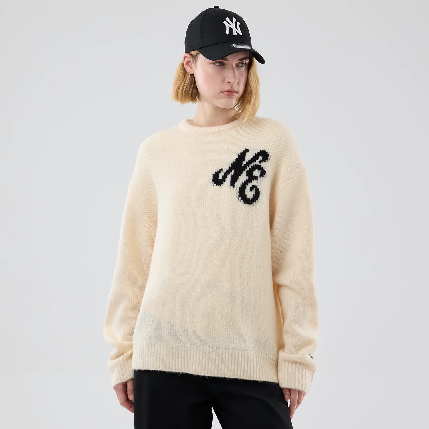 The model is wearing this New Era Knit Knitted Sweater in cream. 4