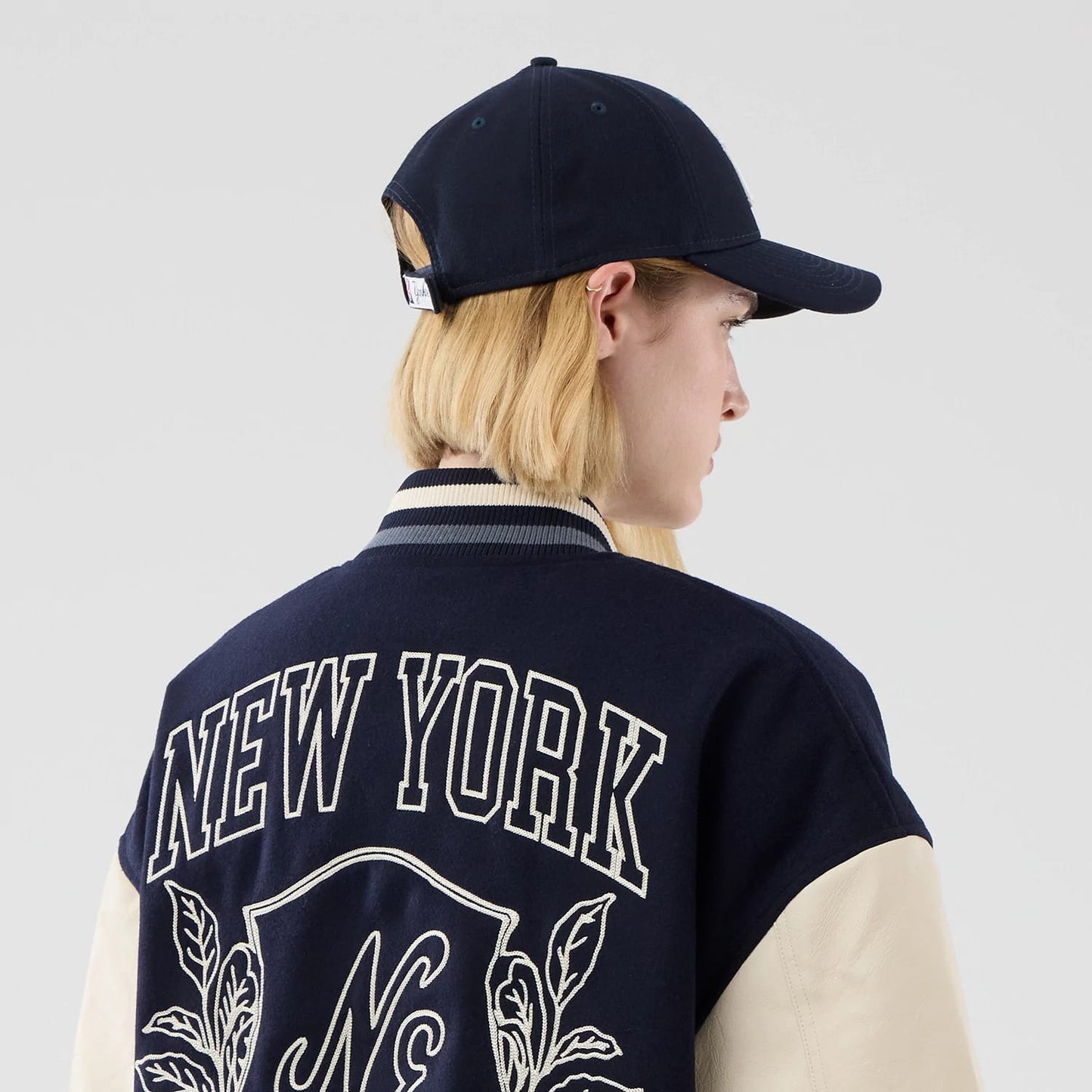 The model is wearing this New Era Oversized Varsity Jacket in navy. 8