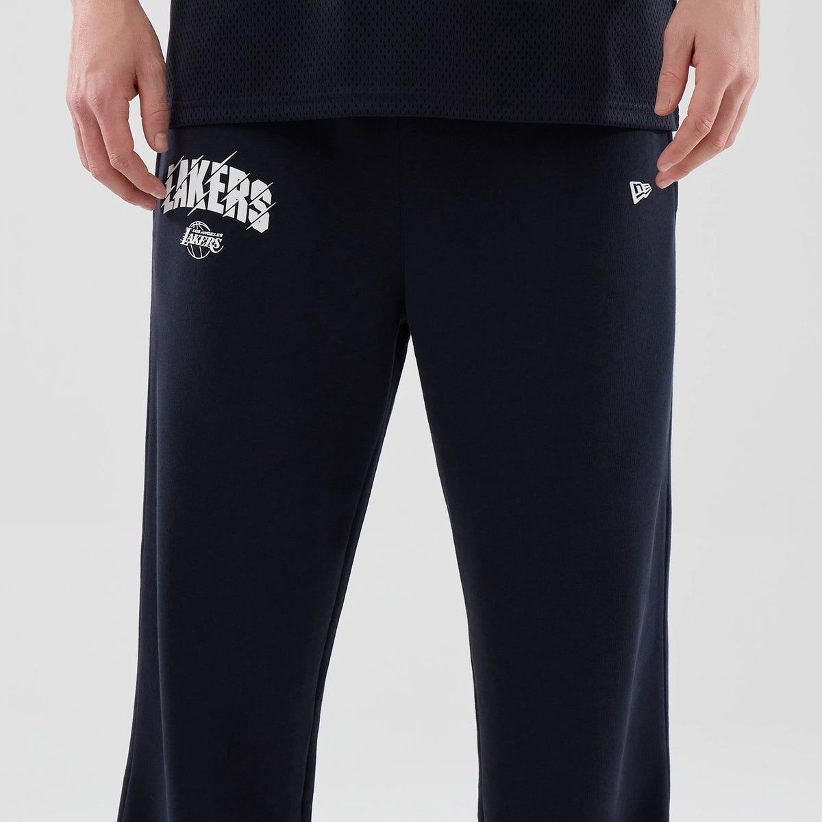 New Era LA Lakers NBA Core Plus Navy Straight Leg Joggers, front view on a model showing the white Lakers text and logo on the left thigh, a New Era flag logo on the right thigh, and a relaxed fit cut.