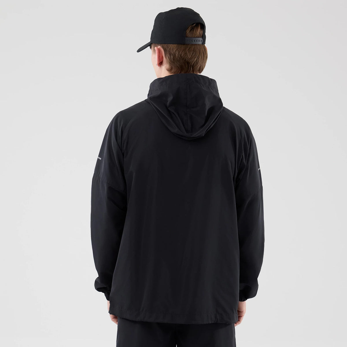 New Era New York Yankees MLB Core Plus Windbreaker Black Jacket, back view on-model showing the hood lying flat, loose fit with long sleeves, and New Era logo on the right sleeve, paired with a black cap.