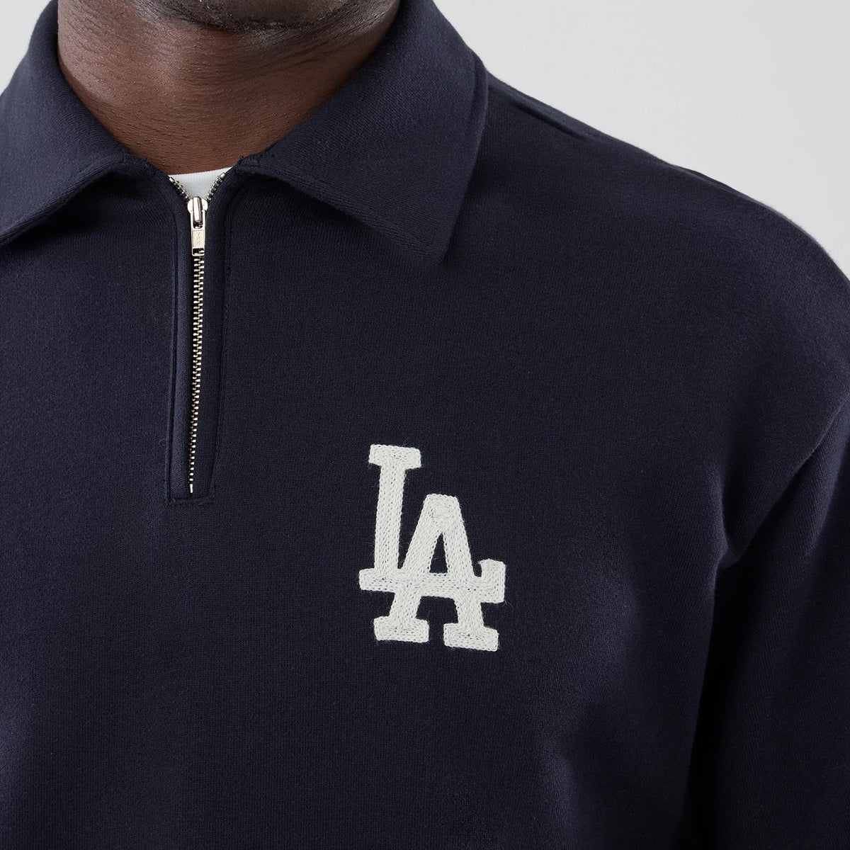 New Era LA Dodgers MLB Navy Oversized 1/4 Zip Sweater, front view on a model showing the white embroidered LA logo on the left chest, a silver quarter-zip closure, and a dark navy fabric with a classic collar design.