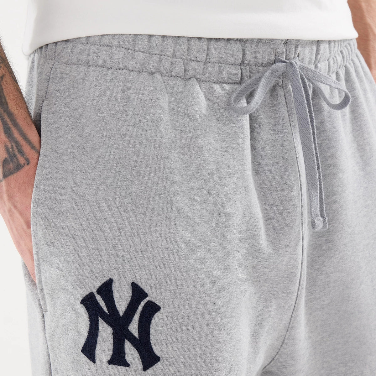 New Era New York Yankees MLB Straight Leg Grey Straight Leg Joggers, close-up view showing the navy NY logo embroidered on the left hip, with an adjustable drawstring waistband and side pocket detail, crafted in light grey fabric.
