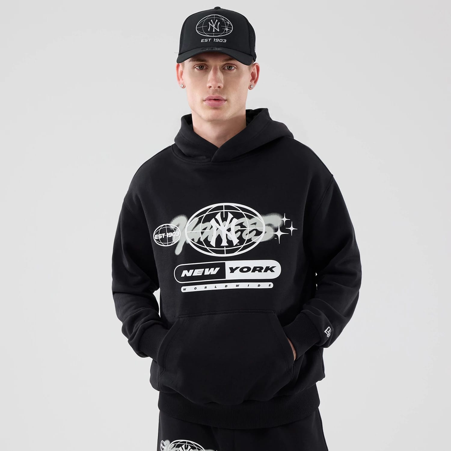 The model is wearing this MLB Logo Graphic New York Yankees Oversized Pullover Hoodie in black. 1