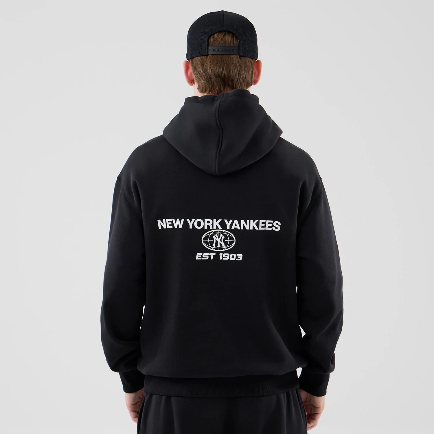 The model is wearing this MLB Logo Graphic New York Yankees Oversized Pullover Hoodie in black. 2