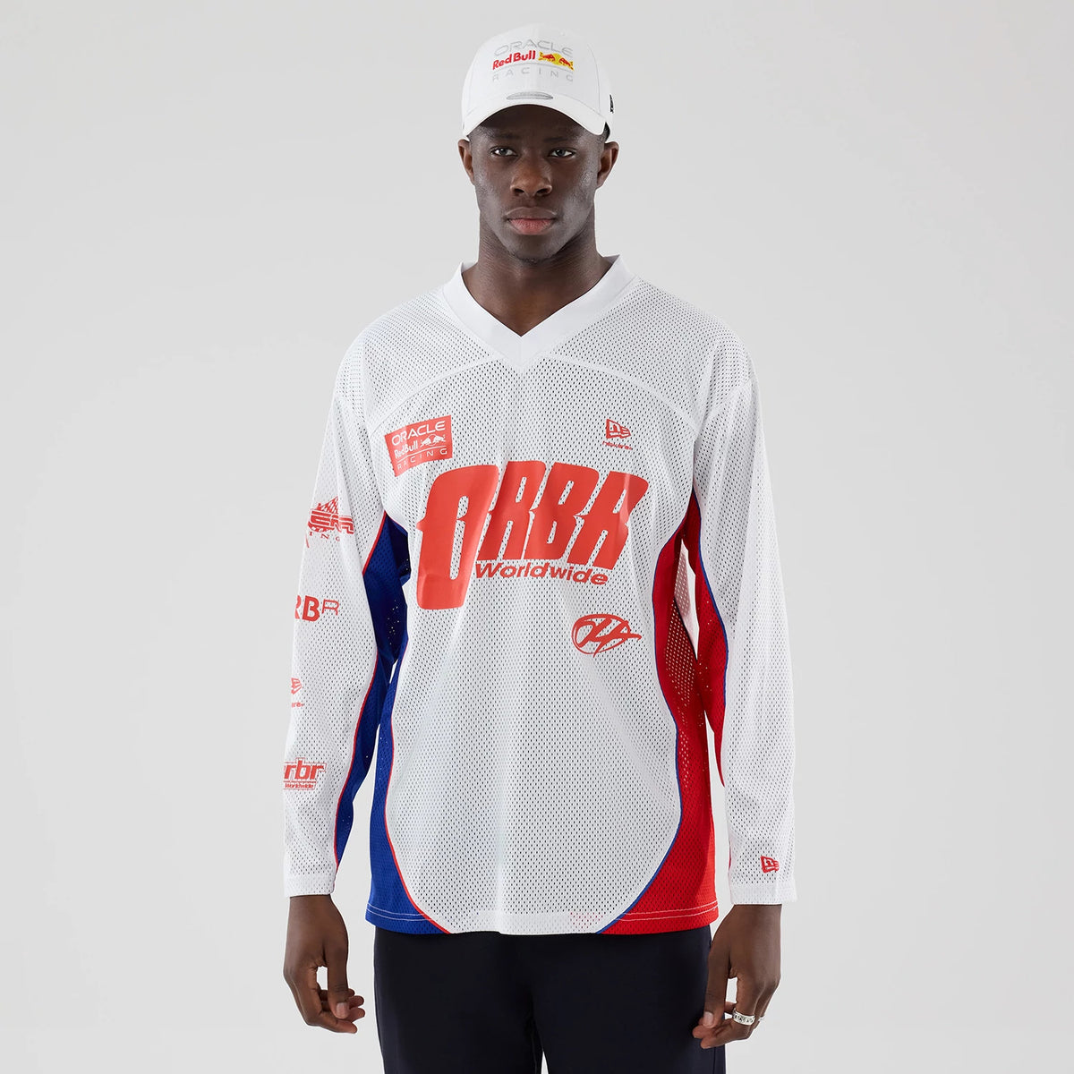 New Era Red Bull Racing White Hockey Jersey, front view on a model featuring red ORBR Worldwide text across the chest, red and blue panels down the sides, and additional branding on the sleeves and chest in red and white.