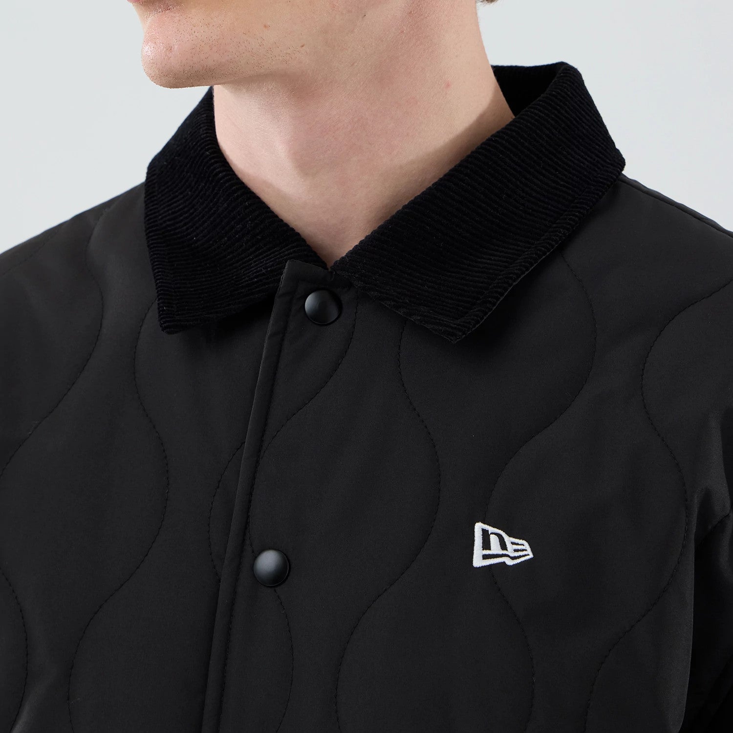 The model is wearing this New Era Quilted Coaches Jacket in black. 4