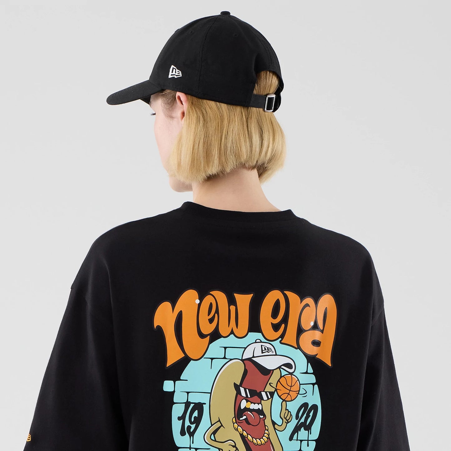 The model is wearing this New Era Hot Dog Graphic Oversized T-Shirt in black. 8