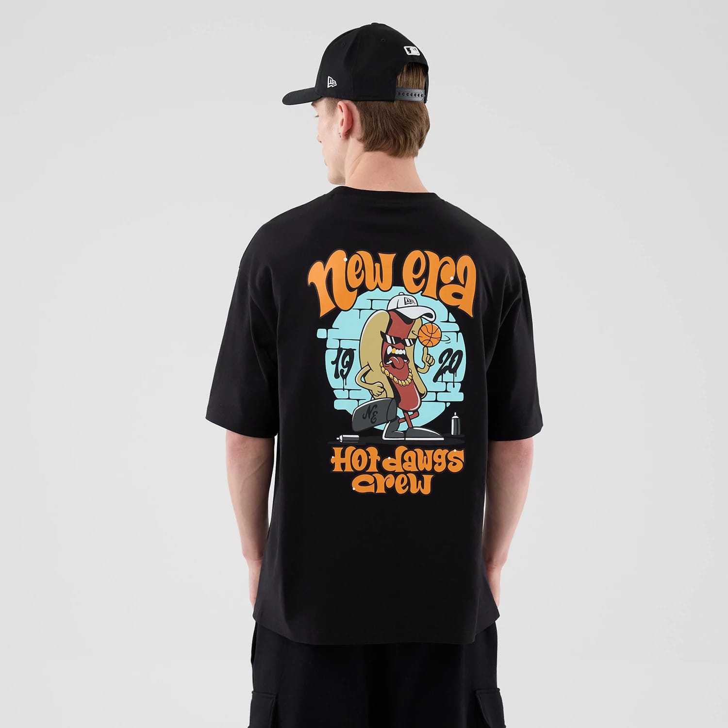 The model is wearing this New Era Hot Dog Graphic Oversized T-Shirt in black. 2