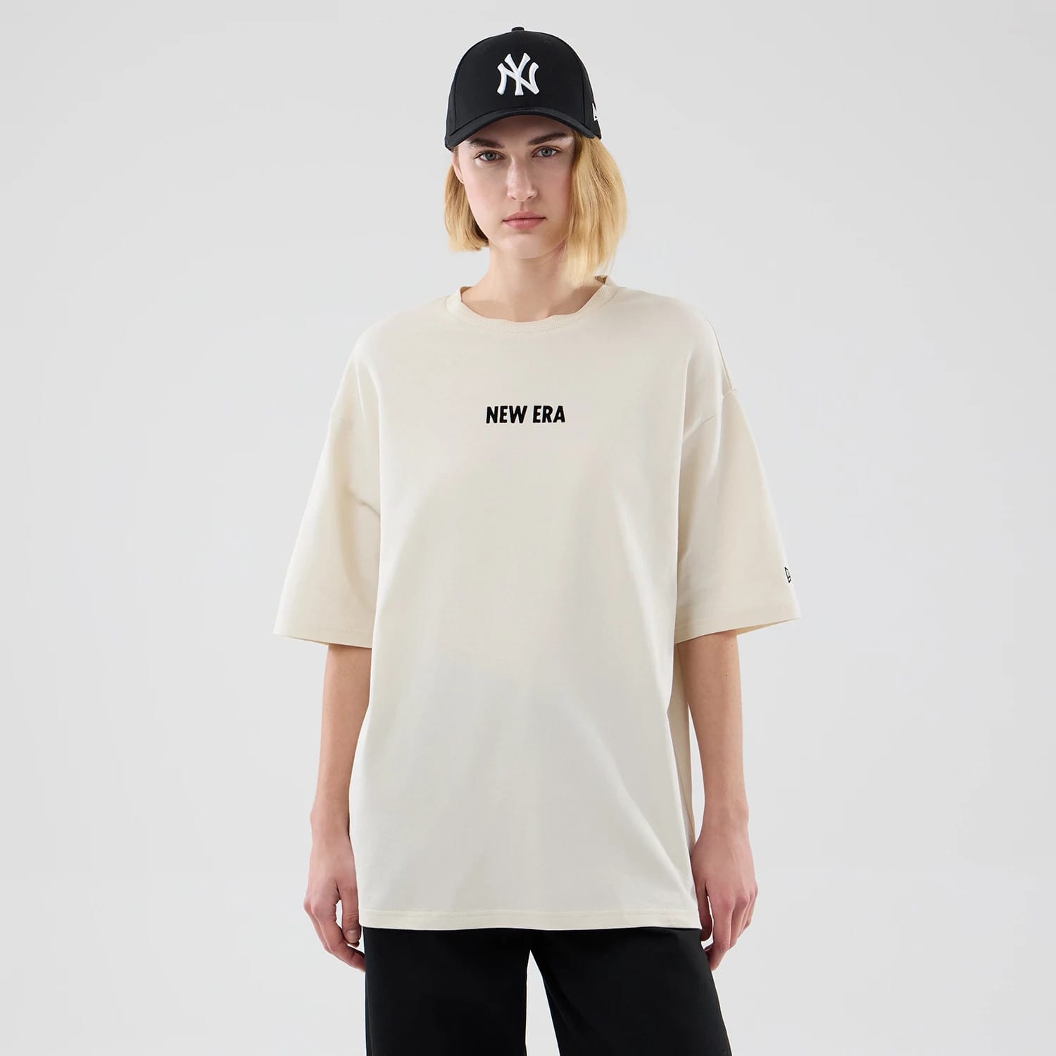 The model is wearing this New Era Cap Graphic Oversized T-Shirt in cream. 4