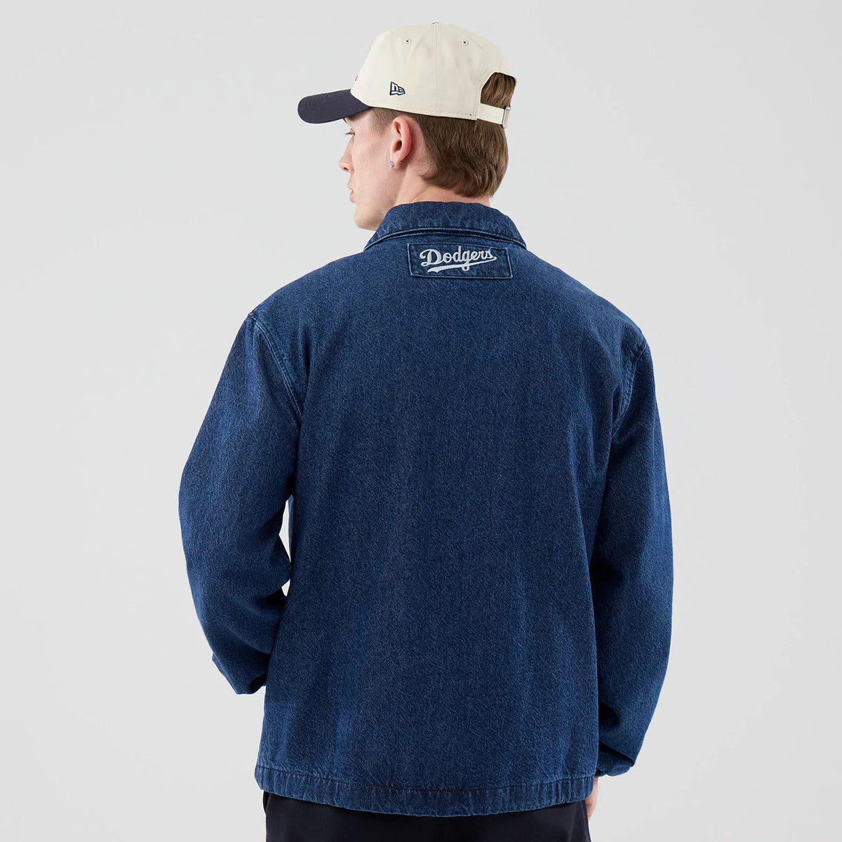 New Era LA Dodgers MLB Coaches Dark Blue Jacket, back view on a model wearing a contrasting cap, showing an embroidered Dodgers logo centred on the upper back, a classic collar and long sleeves with a loose fit.