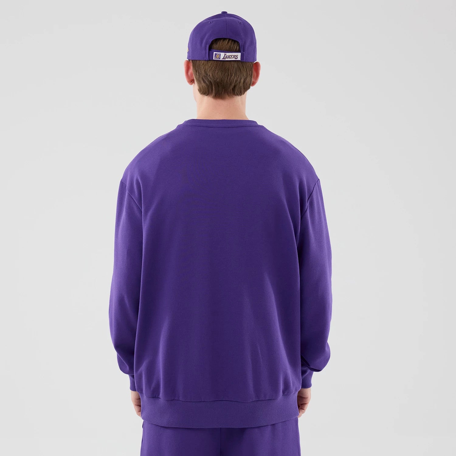 The model is wearing this NBA League Essential LA Lakers Oversized Crew Neck Sweater in purple. 2