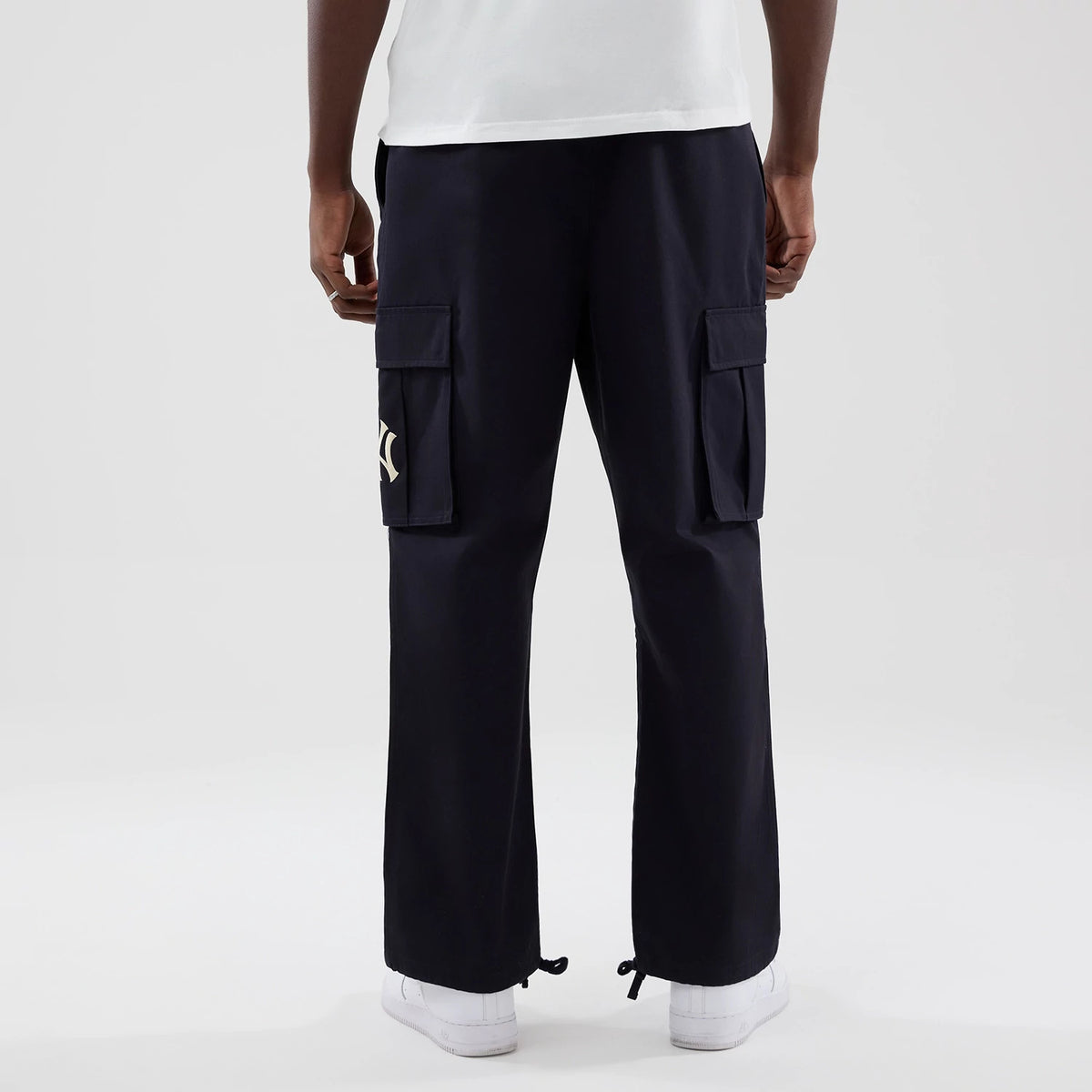 New Era New York Yankees MLB Navy Cargo Trousers, rear view on a model showing spacious cargo pockets on both thighs, the NY logo embroidered on the right pocket, and adjustable drawstrings at the cuffs for a customisable fit.