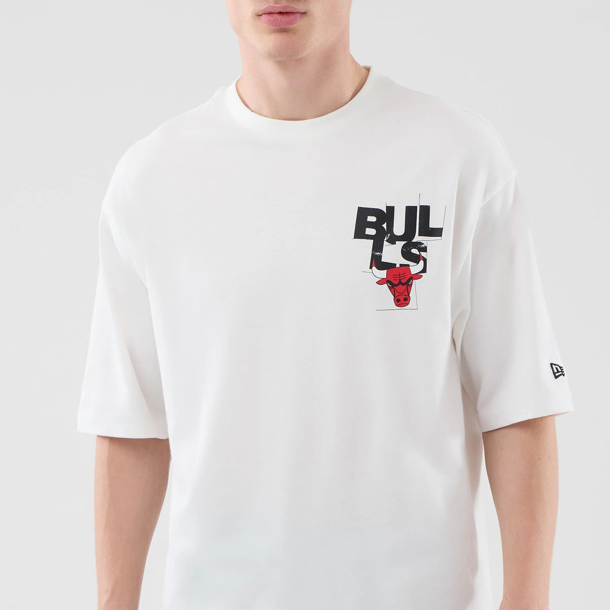 New Era Chicago Bulls NBA Player Graphic White Oversized T-Shirt, front view on-model showing the Bulls logo with a charging bull graphic on the upper left chest, complemented by a black embroidered New Era flag on the left sleeve.