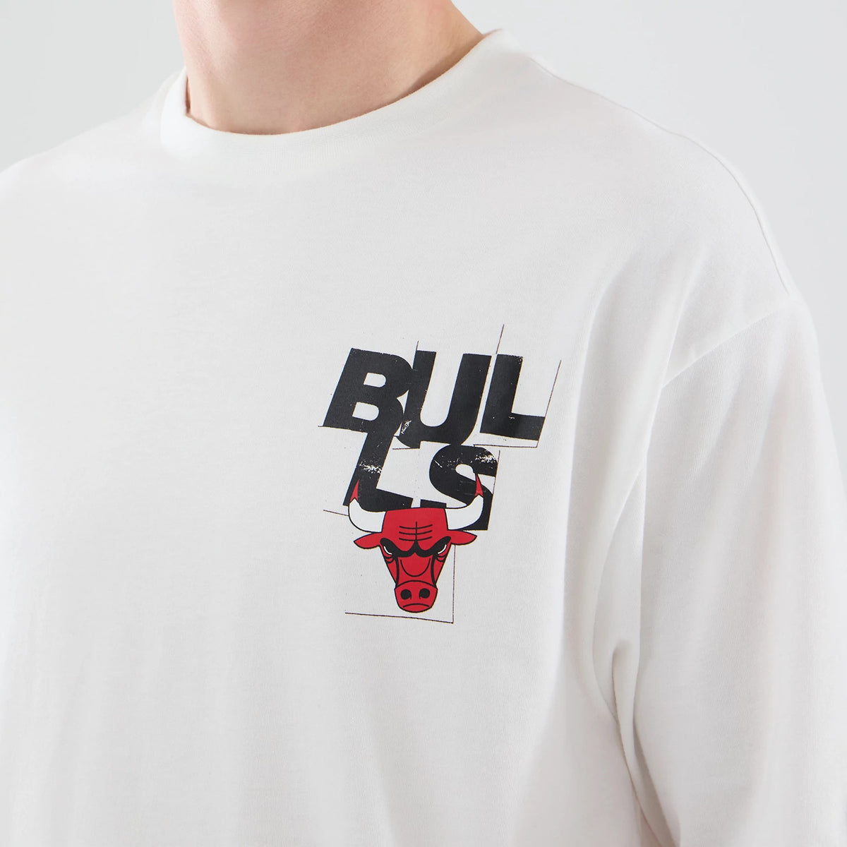 New Era Chicago Bulls NBA Player Graphic White Oversized T-Shirt, front view showing the black distressed BULLS lettering overlapping a red bull logo on the left chest, white fabric with minimal stitching at the neck and shoulder.
