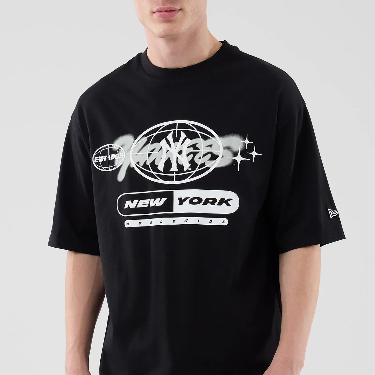 New Era New York Yankees MLB Logo Graphic Black Oversized T-Shirt, front view on a model highlighting the white graphic print featuring the Yankees logo within a globe design, Est. 1903 text, and New York Worldwide wording across the chest.