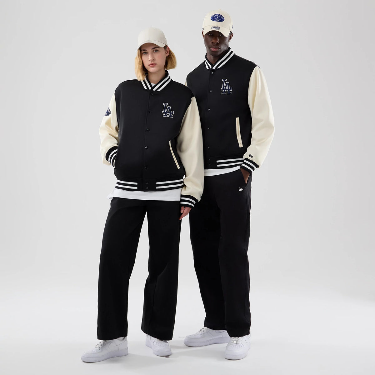 New Era LA Dodgers MLB Jersey Bomber Black Jacket, front view on-model highlighting black body with cream sleeves, an embroidered LA logo on the left chest, striped collar and cuffs, and small New Era logo on the left sleeve.