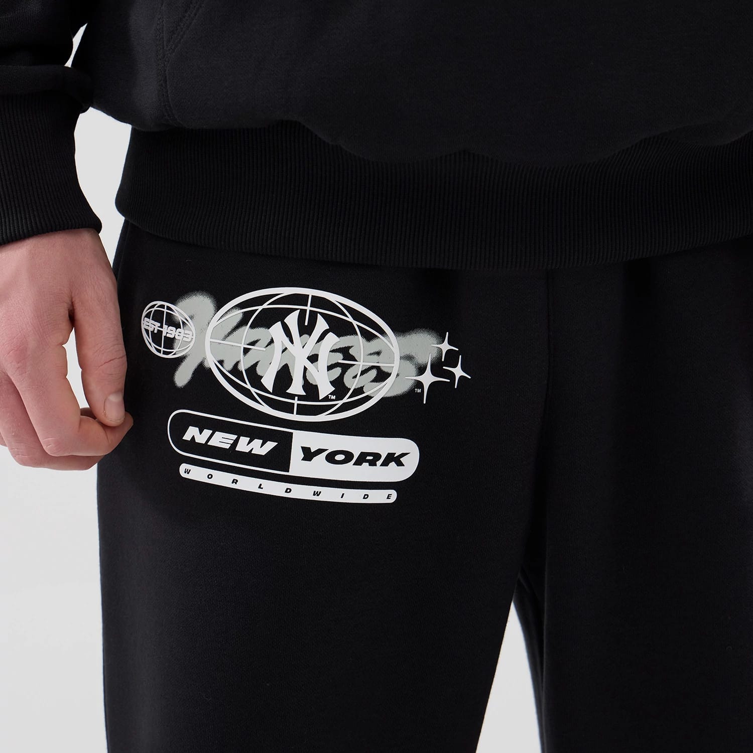 The model is wearing these MLB Logo Graphic New York Yankees Straight Leg Joggers in black. 4