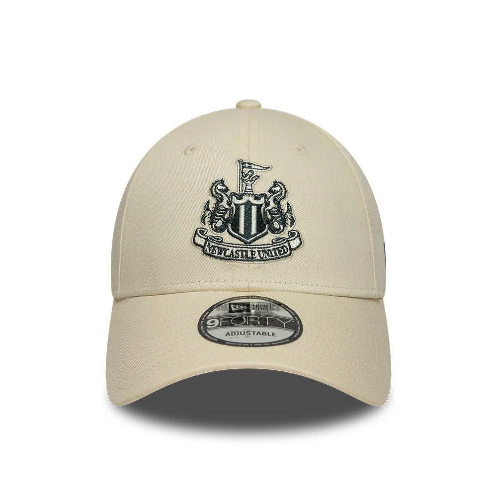 Newcastle United FC Cream New Era 9FORTY Adjustable Cap, front view showing the detailed black and white embroidered Newcastle United crest set prominently on the structured cream front panels, with a 9FORTY size sticker on the curved visor.