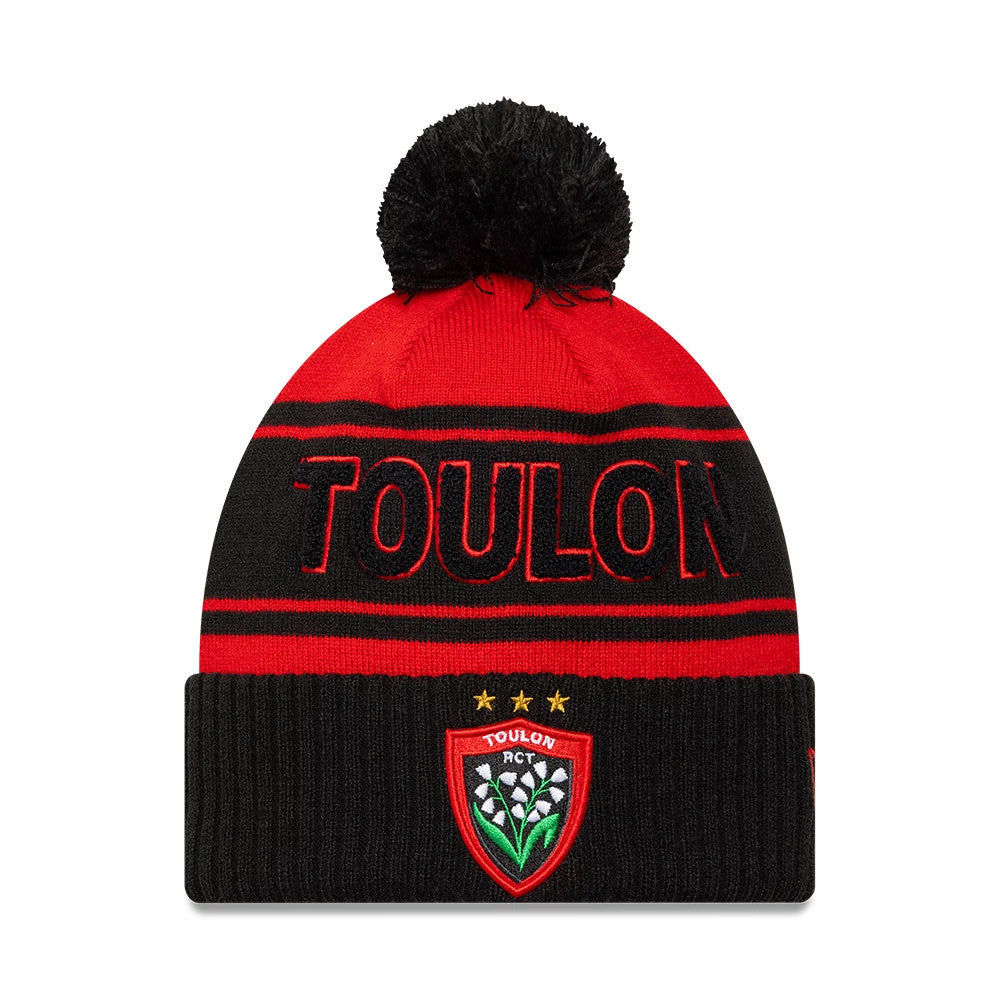 New Era Rugby Club Toulon Black Cuff Knit Beanie Hat, front view showing the black embroidered TOULON lettering across the red section, a large black pom-pom on top, and a detailed embroidered club crest on the folded black cuff.