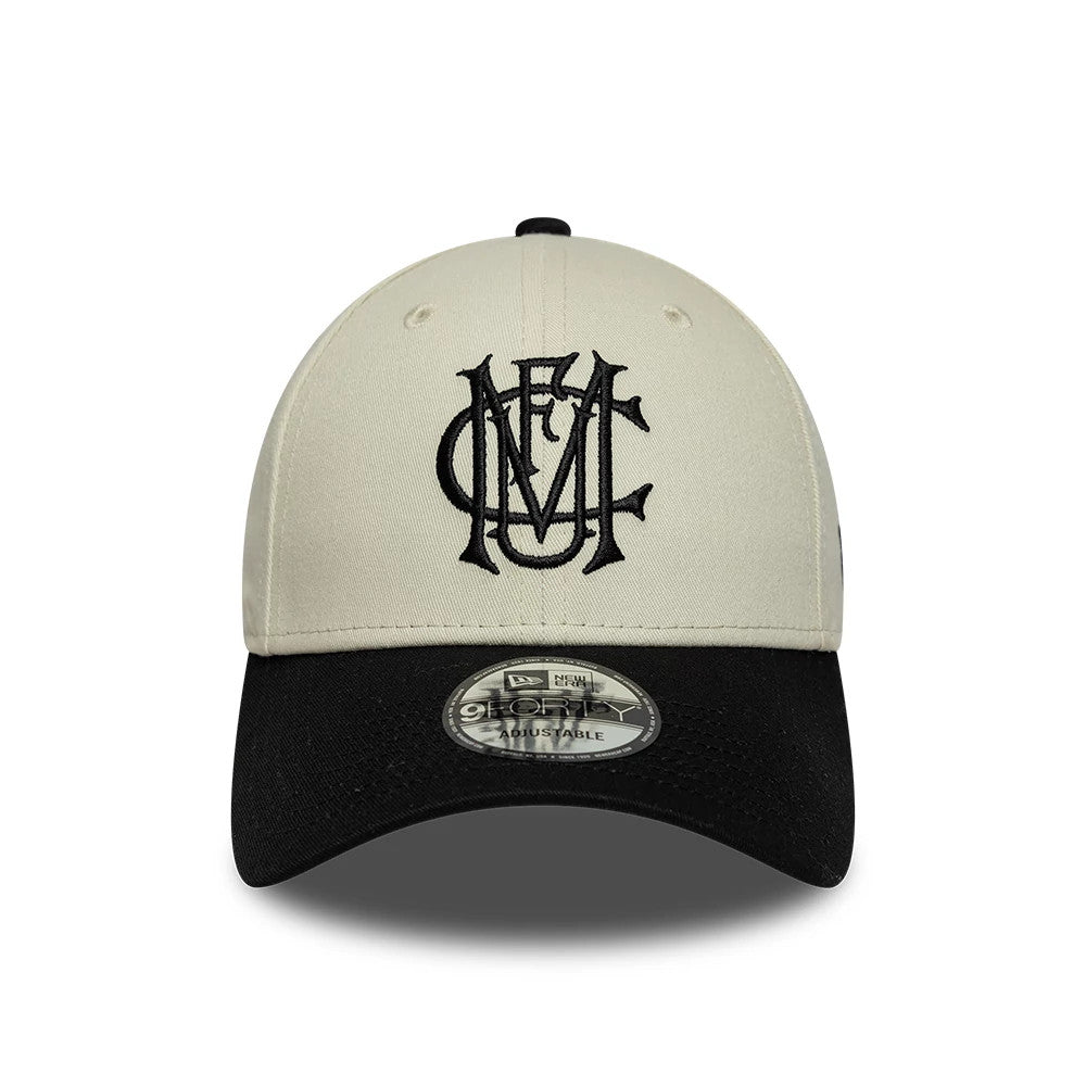 Manchester United FC Monogram Cream & Black New Era 9FORTY Adjustable Cap, front view showing a raised embroidered black monogram logo on the cream front panel, a contrasting black curved visor, and the 9FORTY size sticker on the visor.