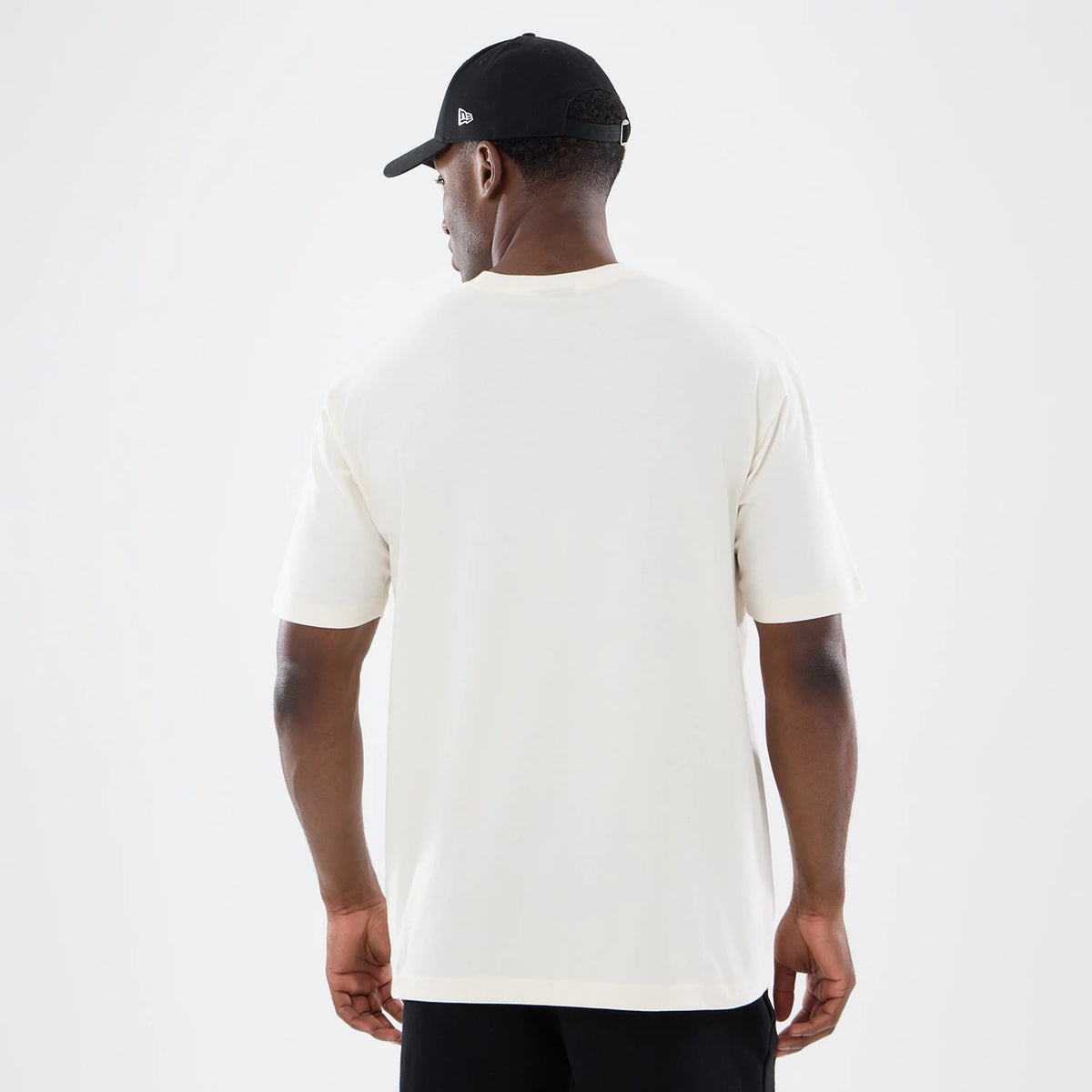 New Era Vancouver Grizzlies NBA Sport Classic Cream T-Shirt, back view on a model styled with a black New Era cap, showcasing the plain cream fabric of the T-shirt with short sleeves and a simple round neckline.