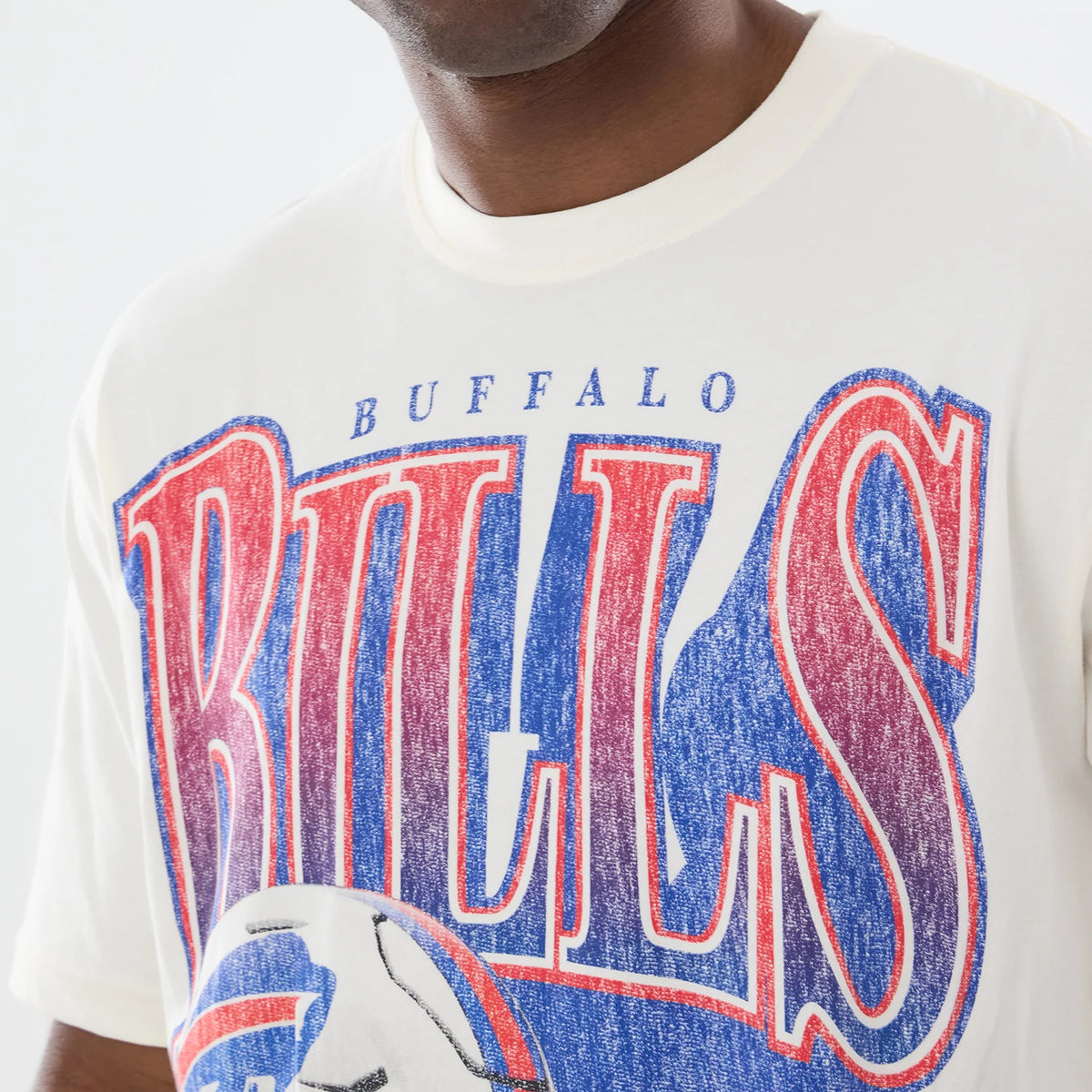 New Era Buffalo Bills NFL Sport Classic Cream T-Shirt, front view showing large distressed red and blue Bills lettering across the chest, a graphic football below, and Buffalo text above, worn by a model in a casual style.