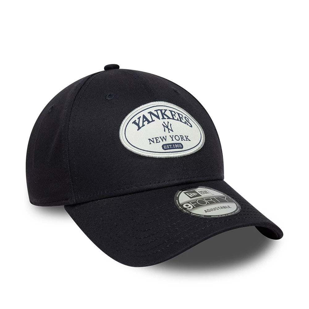 New York Yankees MLB Patch Navy New Era 9FORTY Adjustable Cap, three-quarter view showing a raised oval Yankees New York patch on the front panel, a 9FORTY size sticker on the curved visor, and matching navy crown and top button.