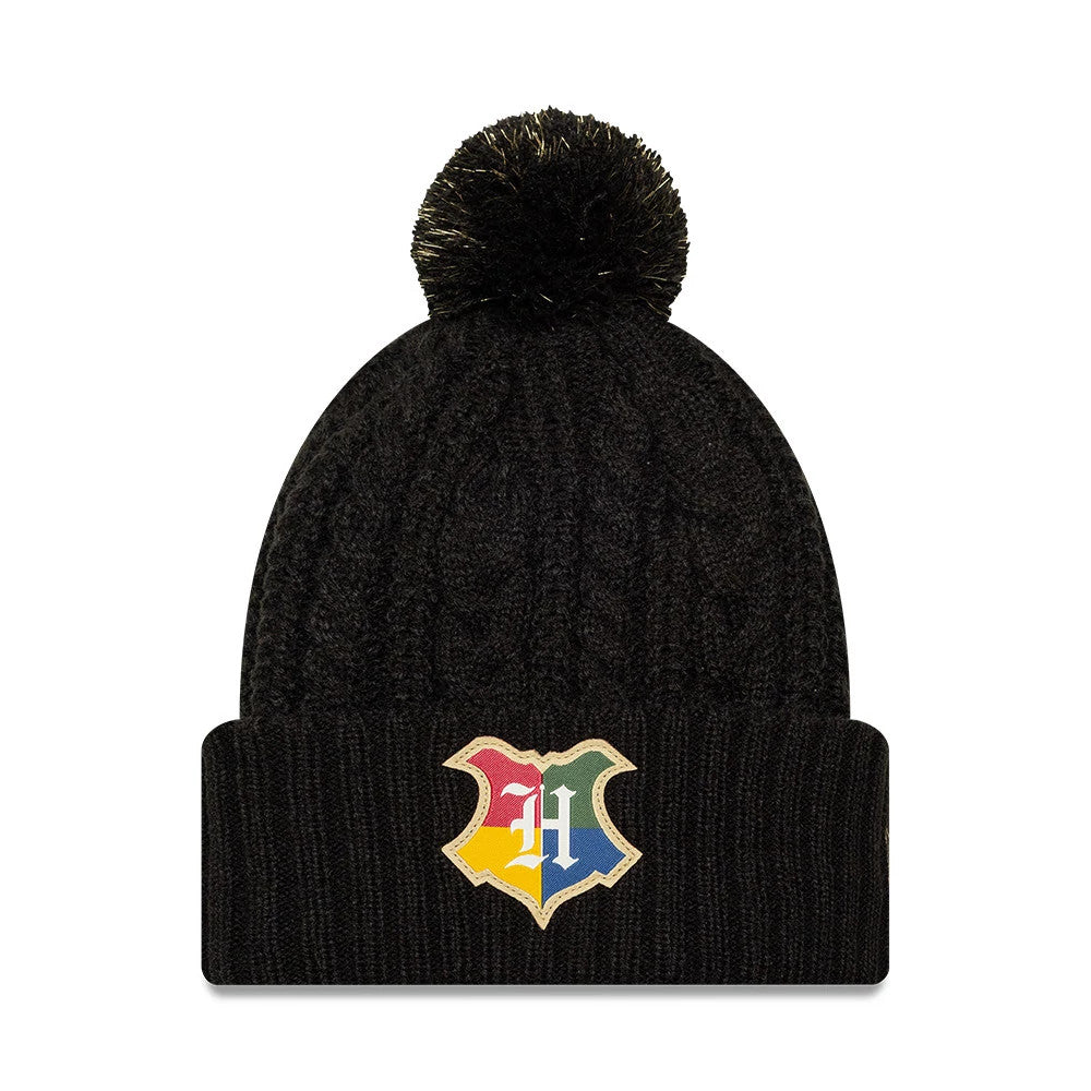 New Era Youth Harry Potter Hogwarts Black Cuff Knit Beanie Hat, front view showing the multicoloured Hogwarts crest embroidery on the cuff, a textured cable knit pattern on the black crown, and a fluffy black pom-pom on top.