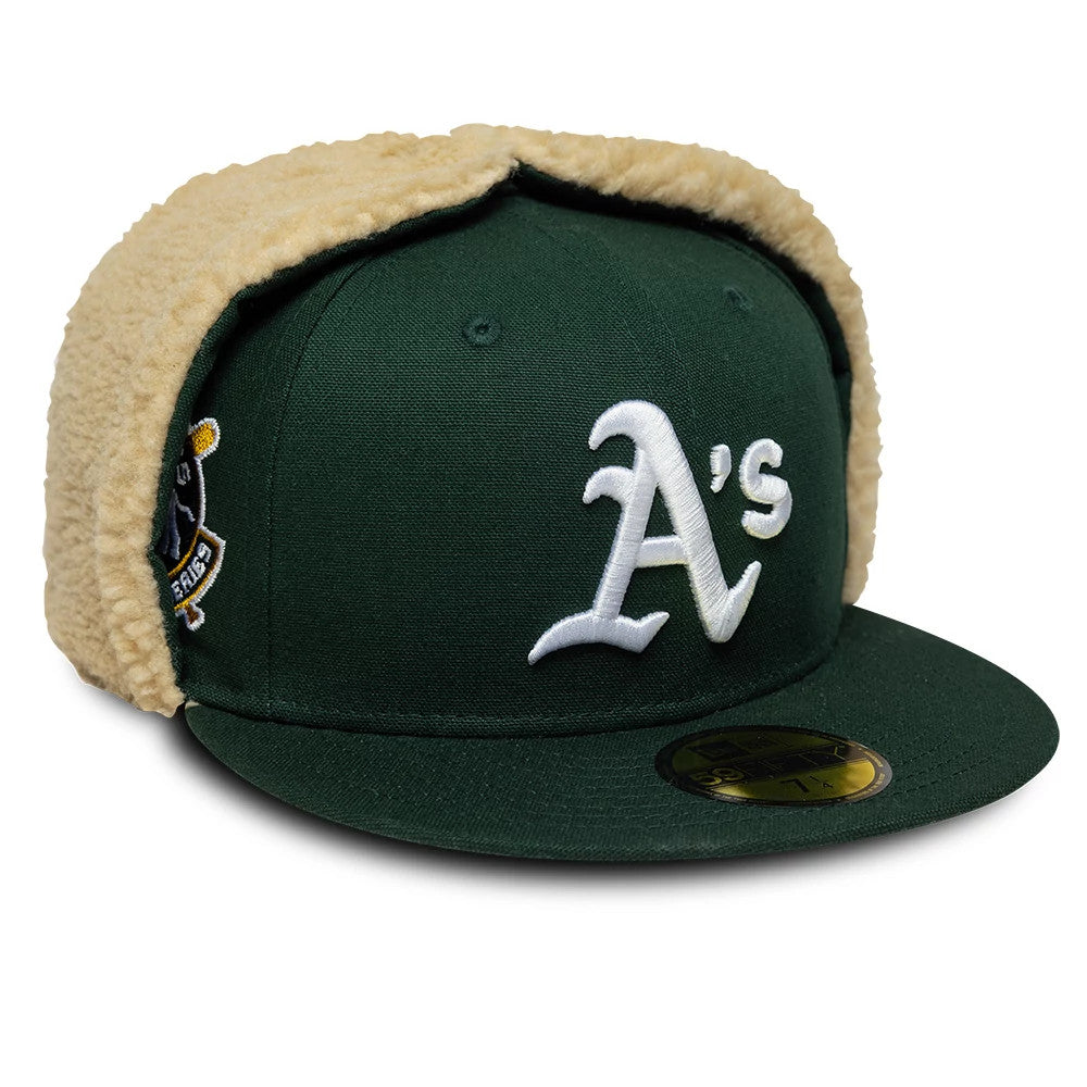 Athletics MLB World Series Dark Green Dogear New Era 59FIFTY Fitted Cap, front view showing the white raised embroidered A's logo on the front panel, a dark green flat visor with gold 59FIFTY size sticker, and beige dogear flaps.