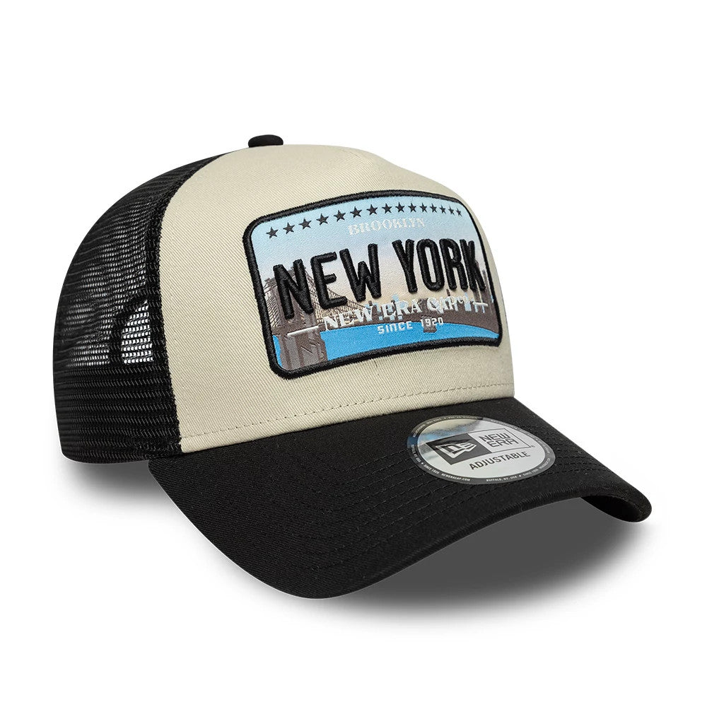 New Era Licence Plate Black New Era 9FORTY A-Frame Trucker Adjustable Cap, three-quarter view showing a unique New York licence plate graphic on the beige structured front panel, a curved black visor with a 9FORTY size sticker, and black mesh sides.