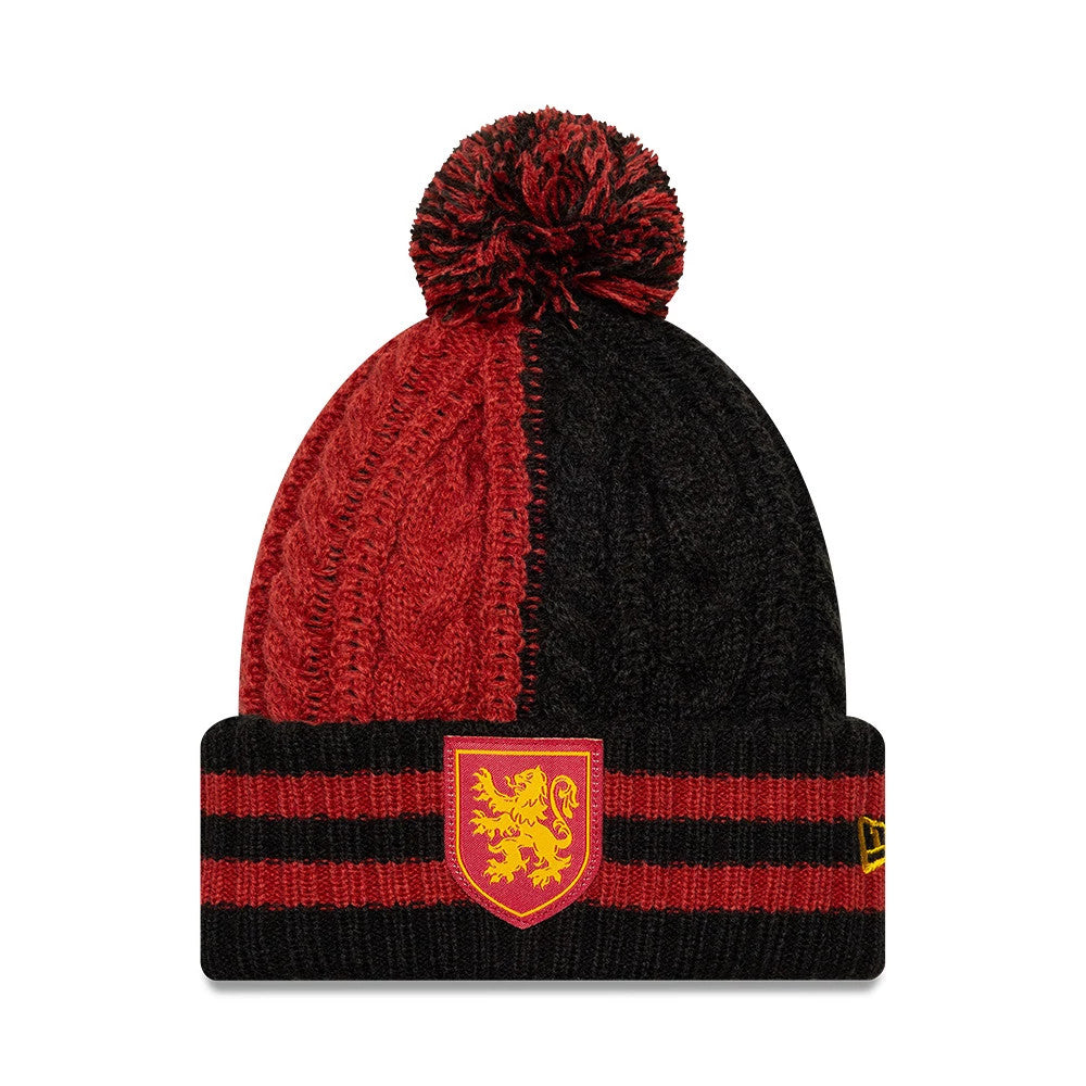 New Era Youth Harry Potter Gryffindor Black Cuff Knit Beanie Hat, front view showing a red and black split design with a fluffy pom on top, red Gryffindor shield emblem on the cuff, and the New Era flag logo on the side.