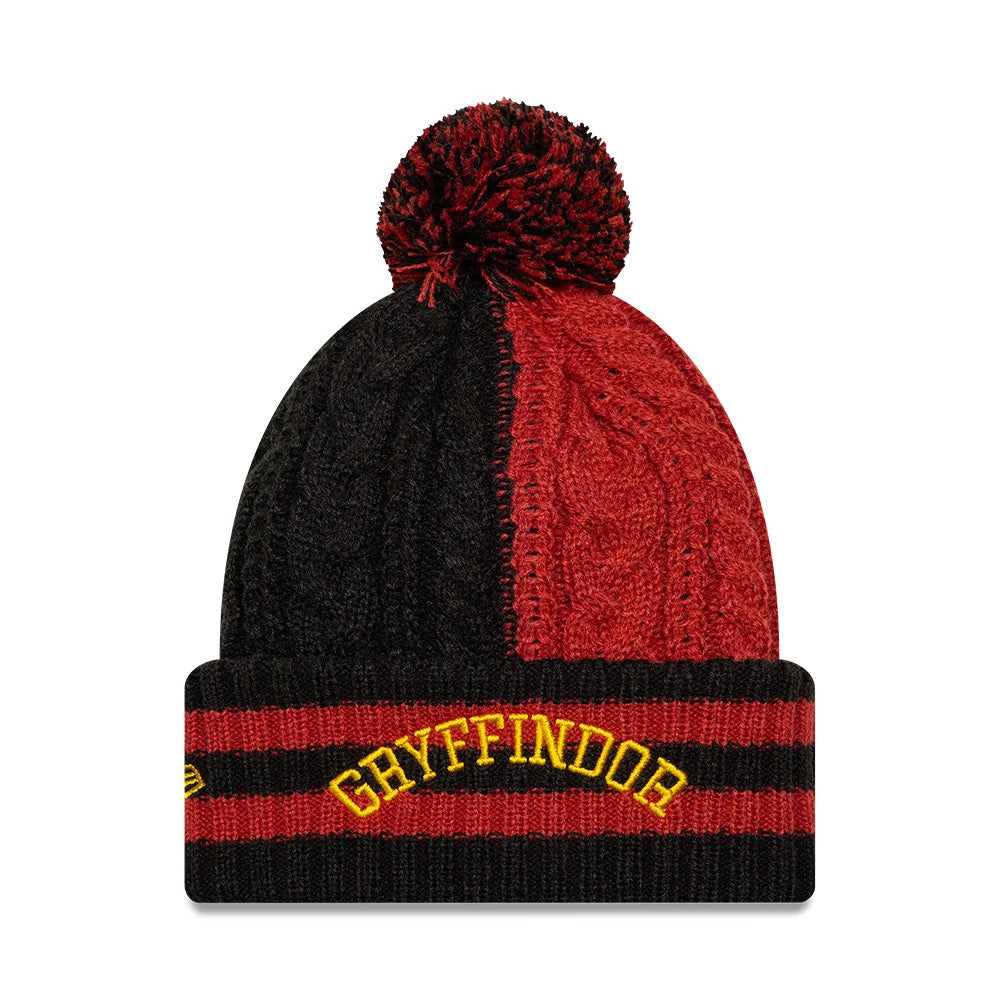 New Era Youth Harry Potter Gryffindor Black Cuff Knit Beanie Hat, front view showing a half-black, half-red cable-knit crown with a matching pom-pom on top, and a folded cuff with yellow Gryffindor lettering and New Era flag logo on the side.