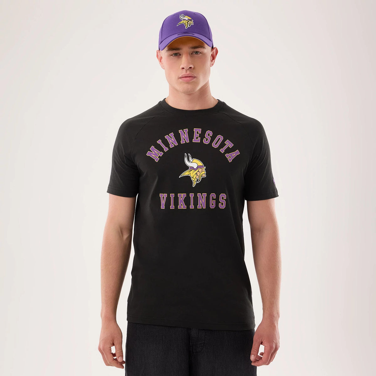 New Era Minnesota Vikings NFL Sideline 2026 Black T-Shirt, front view on a model showing the purple and yellow Minnesota Vikings logo and lettering prominently across the chest, styled with dark jeans.