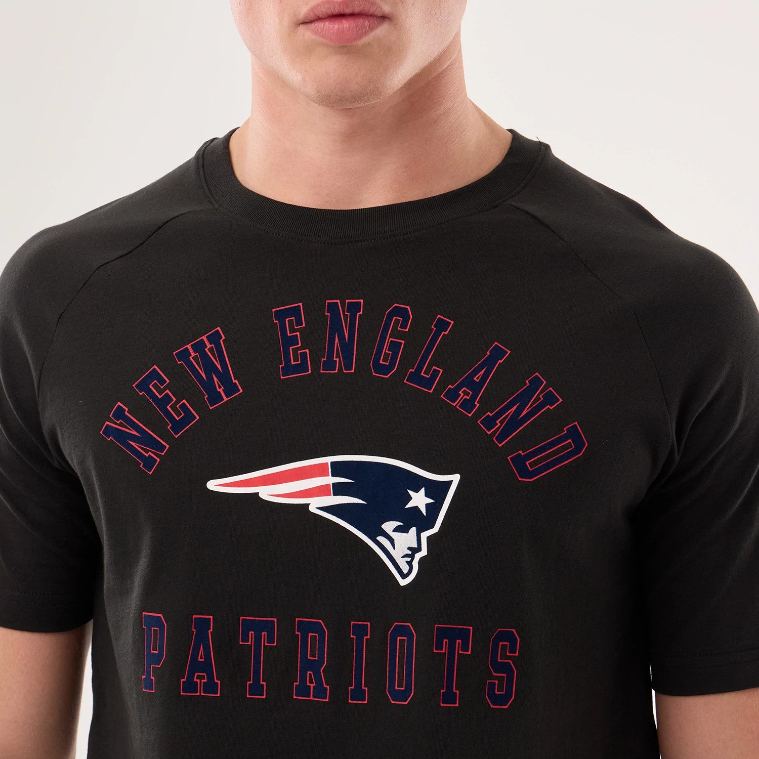 New Era New England Patriots NFL Sideline 2026 Black T-Shirt, front view on-model featuring the red New England lettering arched above the Patriots logo in navy with red and white details, and Patriots text displayed beneath.