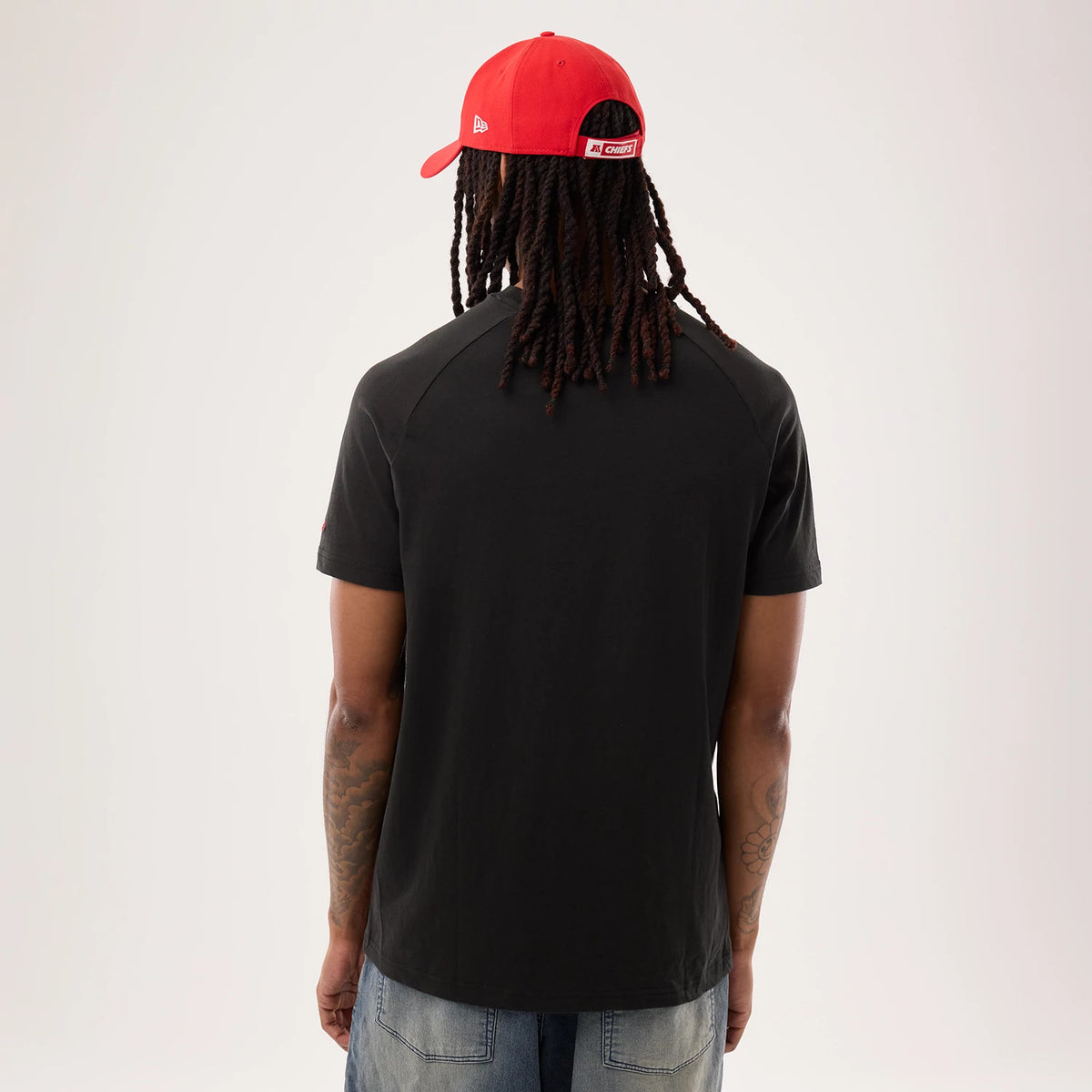 New Era Kansas City Chiefs NFL Sideline 2026 Black T-Shirt, back view on a model with a red cap, showing the plain black back of the T-shirt and short sleeves, creating a clean and classic silhouette.