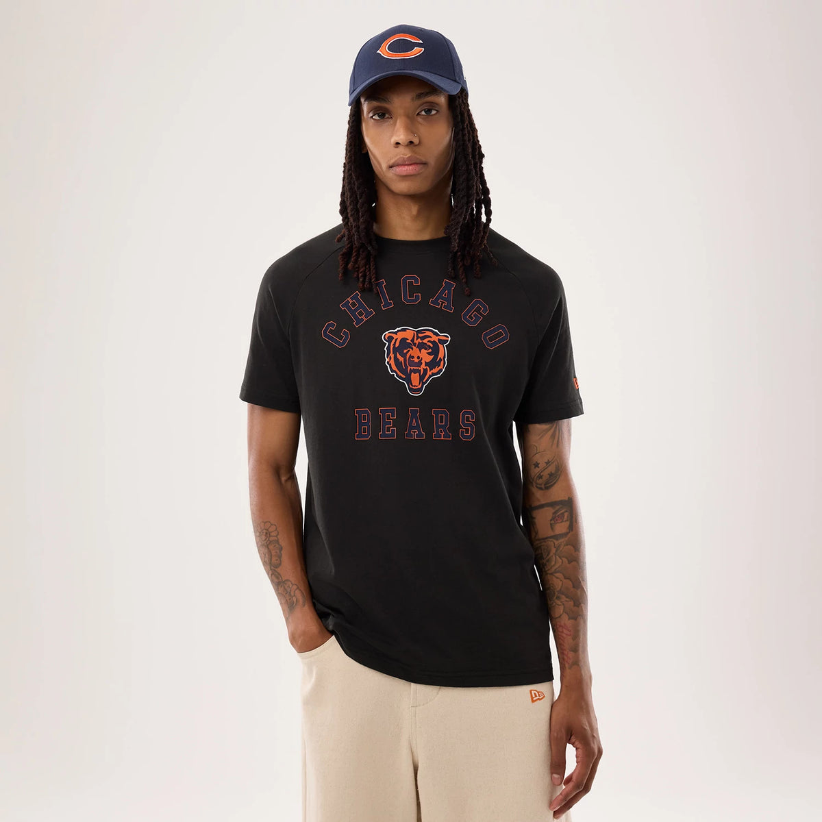New Era Chicago Bears NFL Sideline 2026 Black T-Shirt, front view on a model styled with a blue cap showing a large printed Chicago Bears logo and lettering across the chest, with a small embroidered New Era flag on the left sleeve.