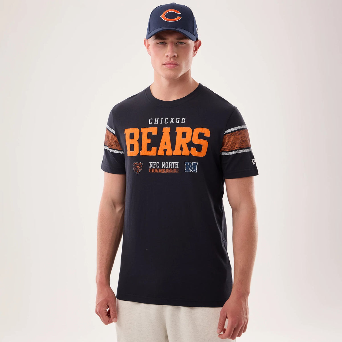 New Era Chicago Bears NFL Sideline 2026 Navy T-Shirt, front view on-model showcasing orange BEARS lettering across the chest with additional graphics below, grey and orange striped accents on the sleeves.
