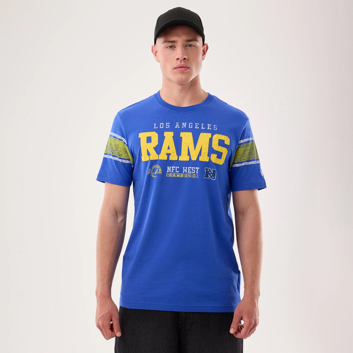 New Era LA Rams NFL Sideline 2026 Bright Blue T-Shirt, front view on a model, showcasing yellow R-A-M-S lettering with a streaked effect, set against the bright blue background, Los Angeles lettering above, and NFC West and Rams logos below.