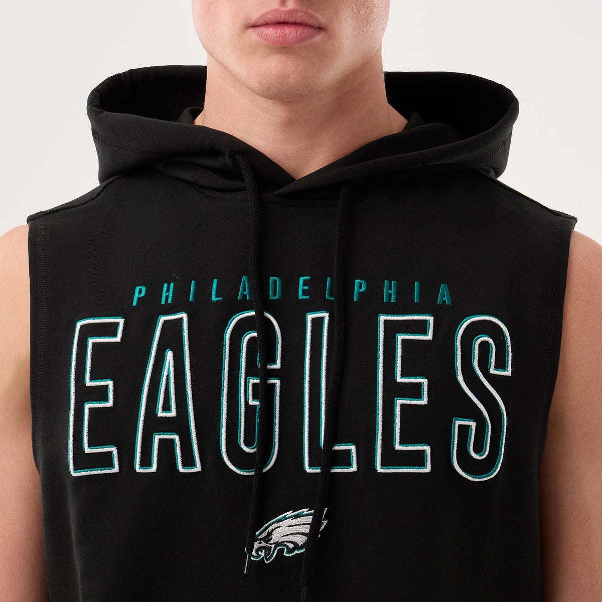 New Era Philadelphia Eagles NFL Sideline 2026 Black Tank Top, front view on a model showing the green and white embroidered lettering of Eagles on the chest, with the team's eagle logo below and a hood with drawstrings.