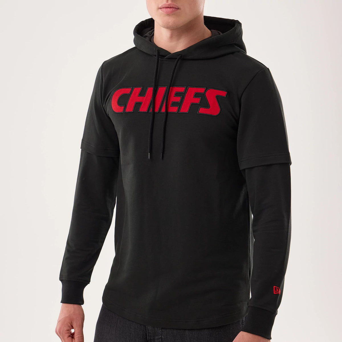 New Era Kansas City Chiefs NFL Sideline 2026 Black Double Sleeve Hoodie, front view on a model featuring a red embroidered CHIEFS logo across the chest, layered sleeve design with the New Era flag embroidered in red on the lower right sleeve.