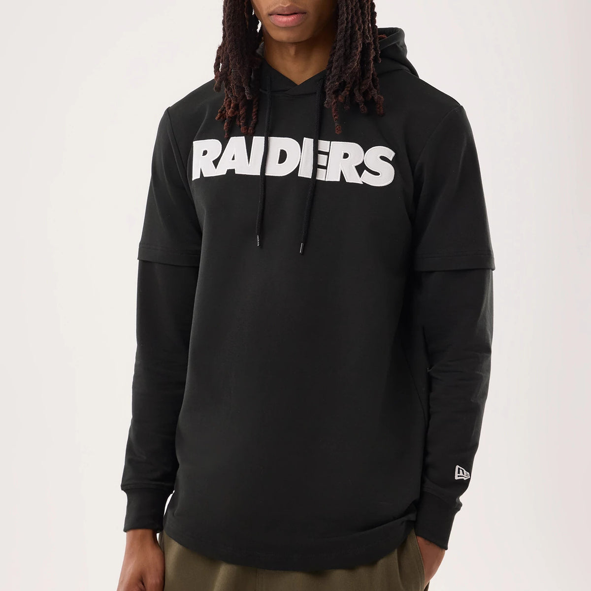 New Era Las Vegas Raiders NFL Sideline 2026 Black Double Sleeve Hoodie, front view on a model highlighting the white embossed RAIDERS across the chest, layered double sleeves with cuff details, and an embroidered New Era logo near the left wrist.