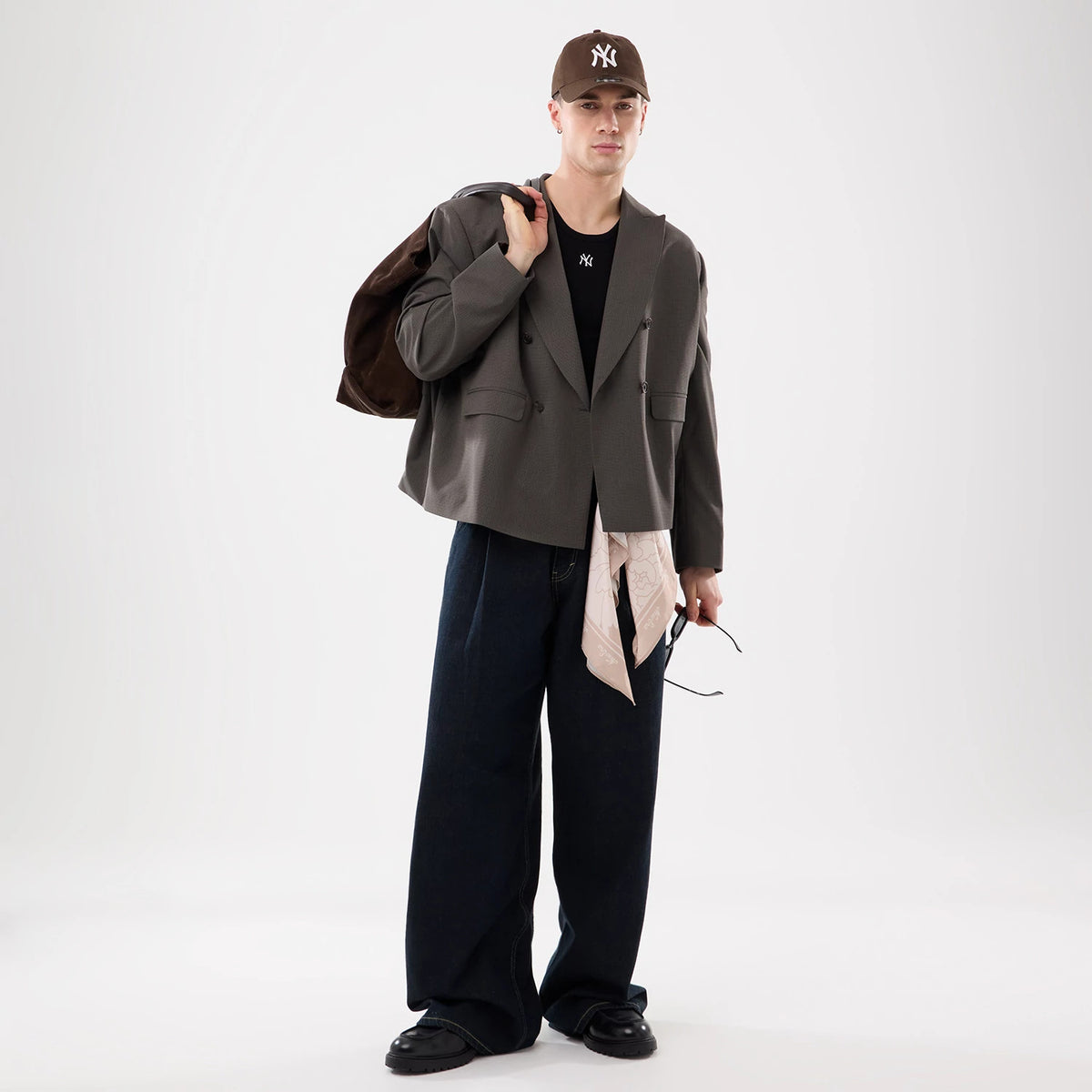 New Era Floral Satin Beige Bandana, on a model styled with a beige cap and beige bandana over a layered outfit, including a grey jacket and wide-legged denim trousers, with the bandana draped from the model's waist.
