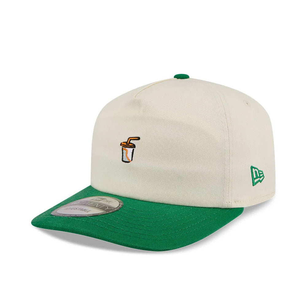 New Era Juice Cream 19TWENTY Adjustable Cap, three-quarter view showing an embroidered juice carton graphic on the front cream panel, complemented by a green curved visor with a 19TWENTY size sticker, and a green New Era flag logo on the left side.